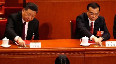 A photograph of Xi Jinping and Li Keqiang voting. Xi uses his index finger to vote, while Li Keqiang uses his middle finger. 