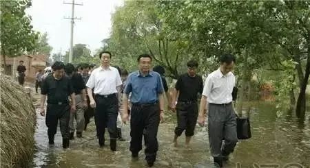 Li Keqiang and a group of officials wade through ankle-high floodwaters in a rural area of Henan.